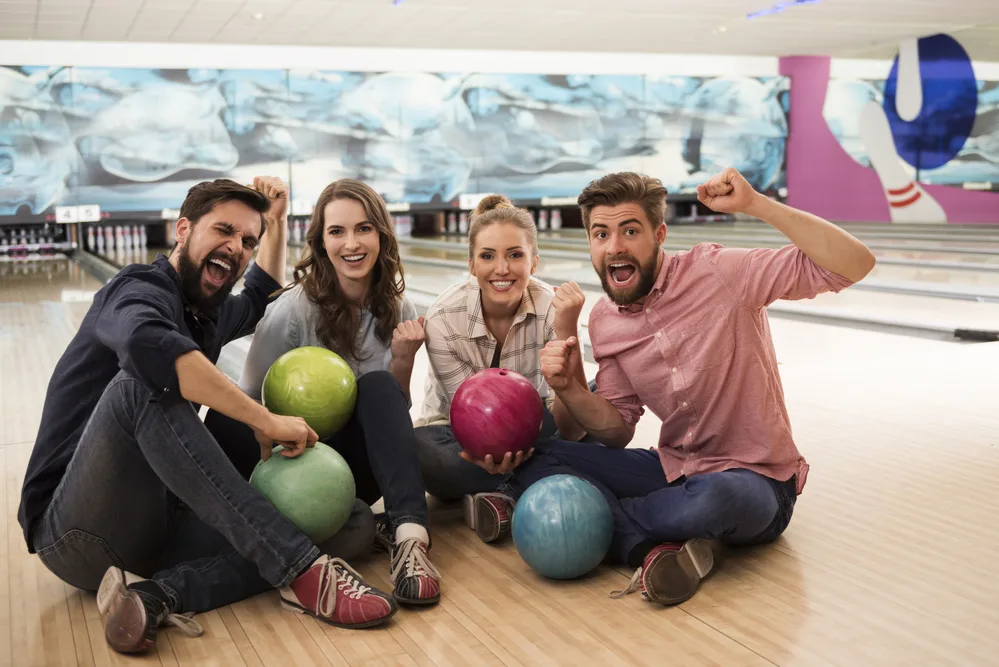 Bowling mates sitting on the lane cheering. They have more natural competition and love the game of bowling