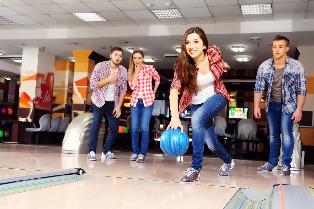 Friends playing in bowling club and rolling a urethane ball