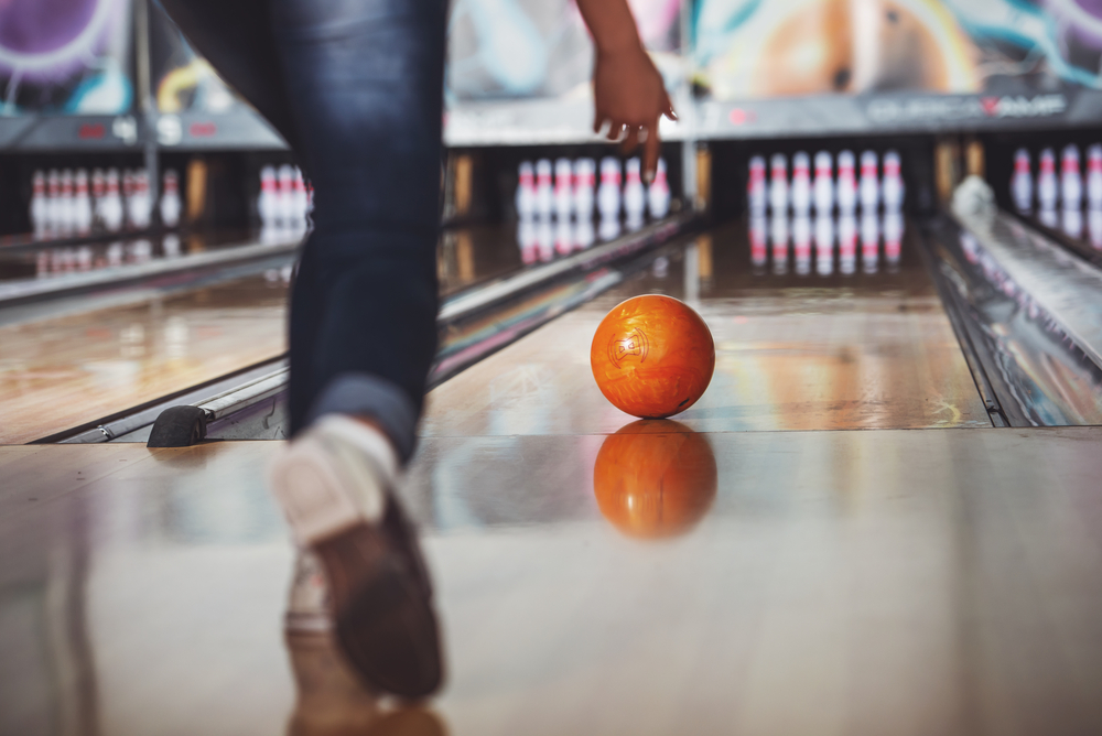 Woman in a bowling club for bowling is throwing ball and getting little ball reaction