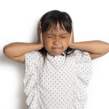 Little girl covering ears loud noise at bowling alley