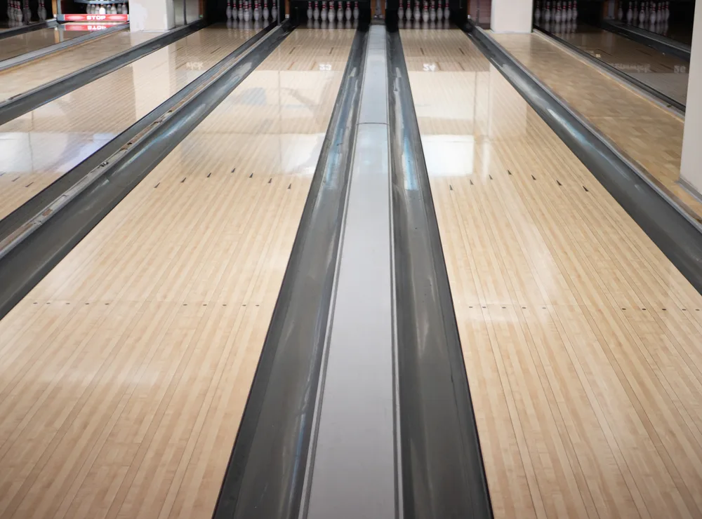 Brower of the lane doesn't show the oil pattern on the two lanes tracks at bowling club with a bunch of bowls pins browser upt the lane.