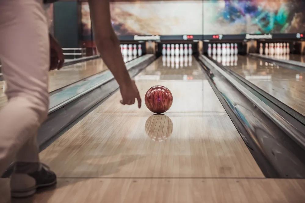 Image of a man throwing a red bowling ball down the center boards