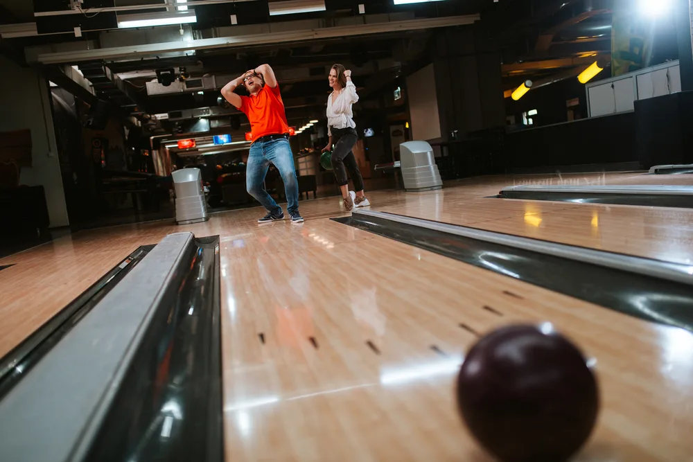 The bowler in the red shirt rolled the black bowling ball and remember his break point was roughly around the 8 board.