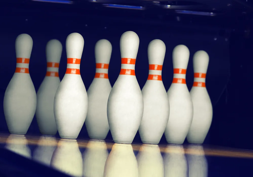 Bowling pins on a lane were a team is practicing their bowling technique to up their game to 300