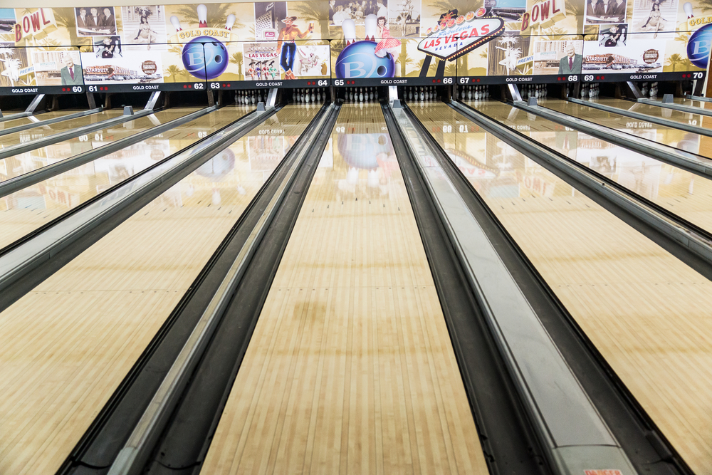 Bowling lane with pins at the end has the sunset strip pattern where the outside part of the lane is drier
