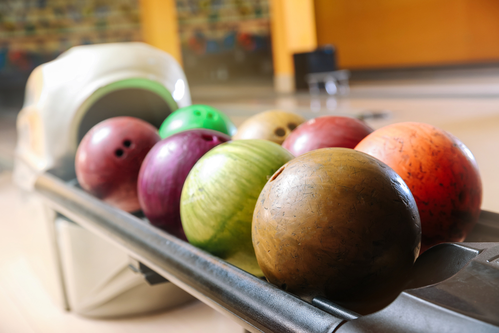 Eight different bowling balls on the ball return all have three finger holes