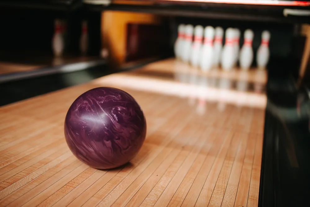A plastic or rubber bowling ball on a lane approaching the pins