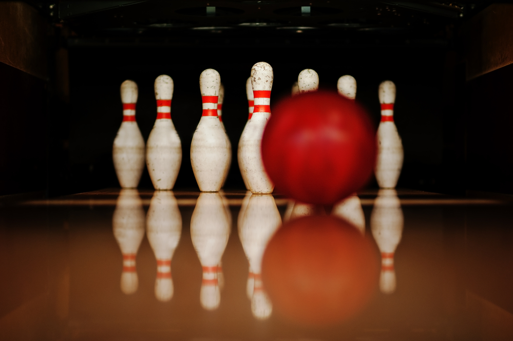 Ten white bowling pins in a bowling alley will be a strike depending on where the  red bowling ball hit