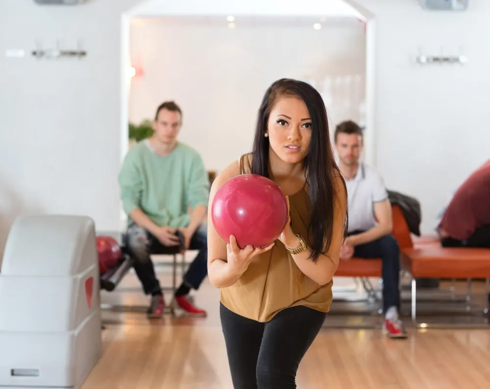 The girl bowler with the red bowling ball is practicing to be the first female bowler to enter and win the men's tour.