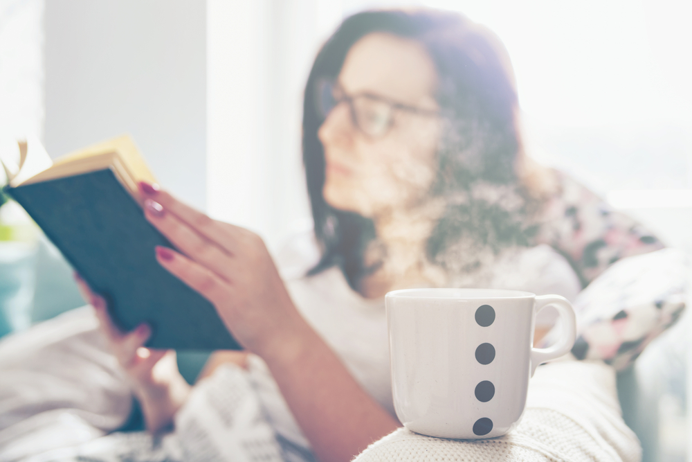 Relaxed woman drinking coffee and reading bowling popular bowling books to increase her skills.