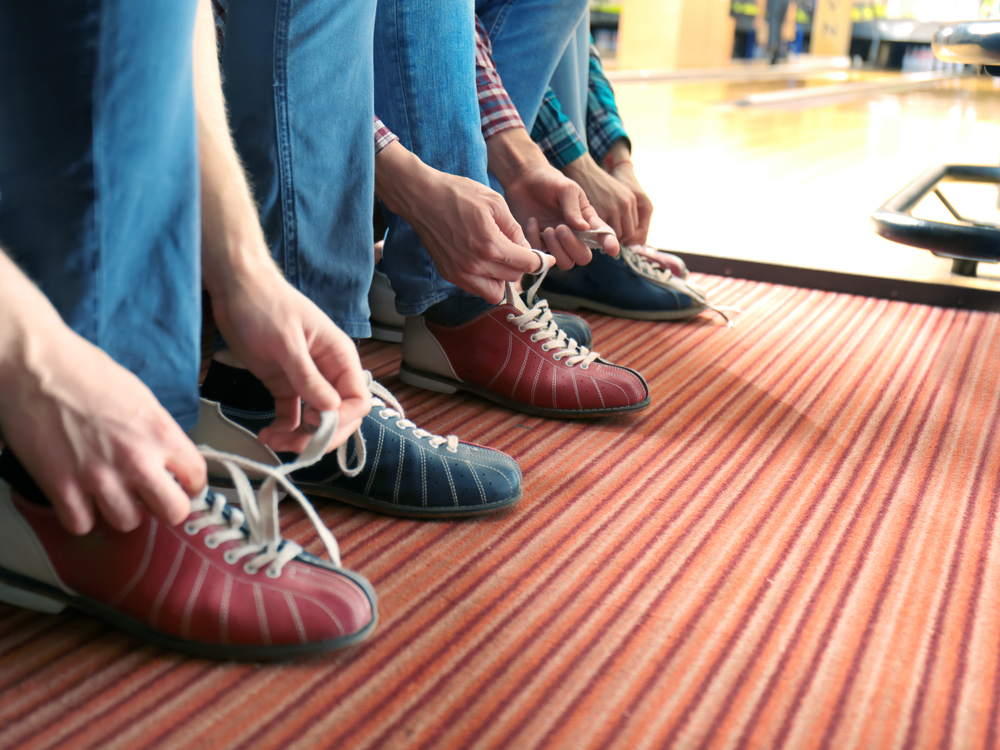 Friends lacing their shoes in bowling club