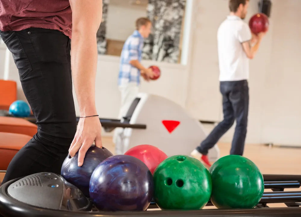 Male bowler picking up blue bowling ball at a thirty lane alley