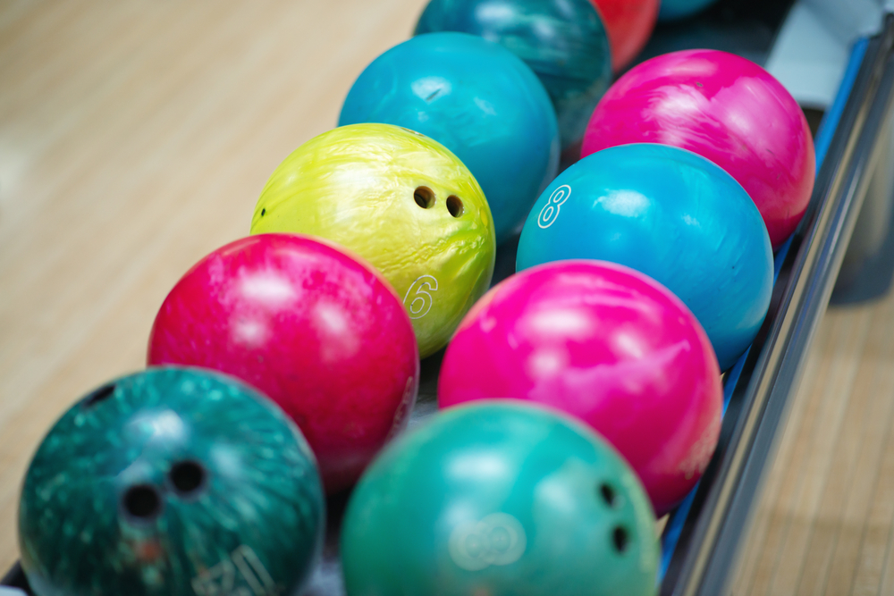 Different colored used bowling balls on a ball return