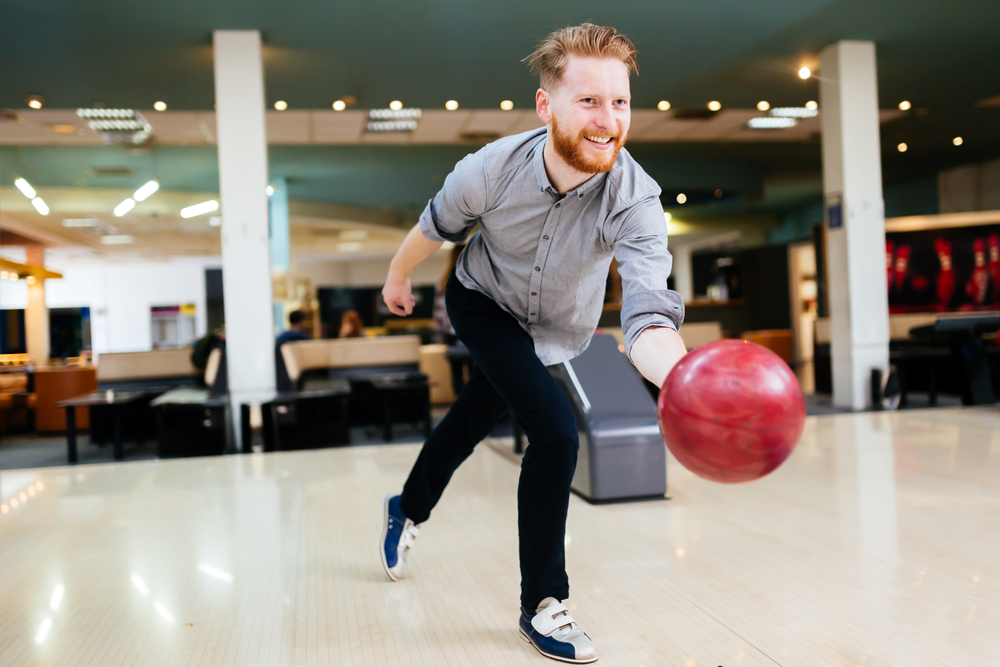 Man rolling a red bowling ball trying to keep the break point closer to the pocket