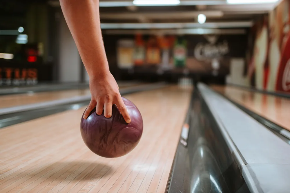 Man bowling purple ball on dry lane conditions