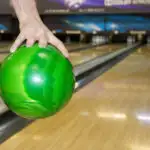 Man bowling with green ball to much oil on lane