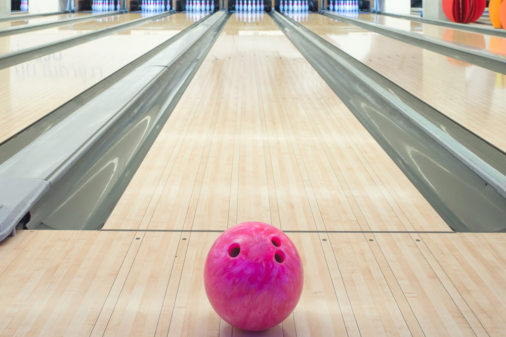 Pink bowling ball on lane that has a wax finish