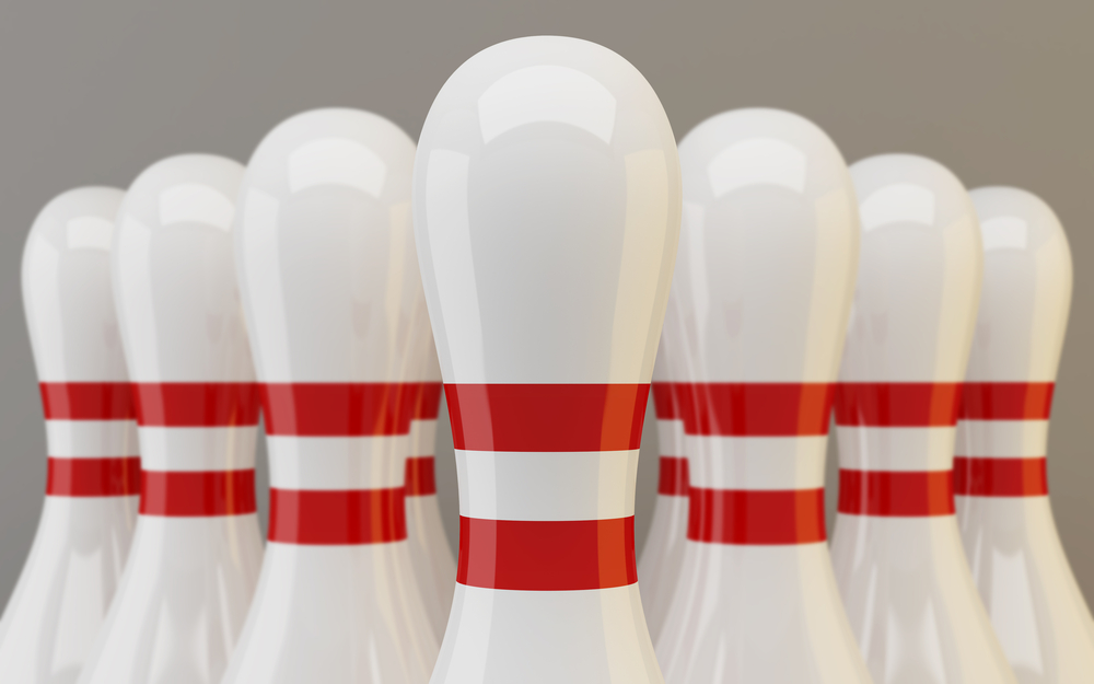 Group of bowling pins closeup on gray background waiting to be hit by bowling balls