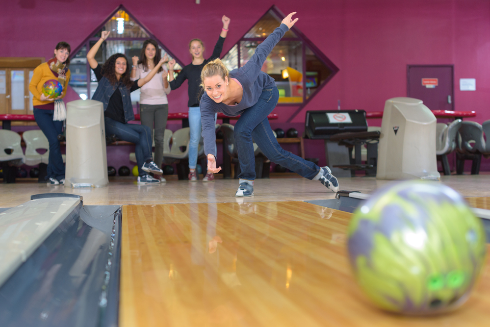 A woman bowler with blue bowling shoes at her local bowling alley rolled a strike
