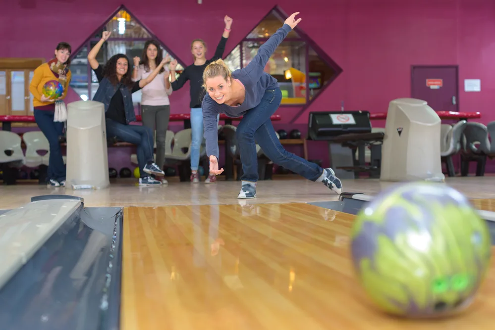 Woman bowling and friends cheering