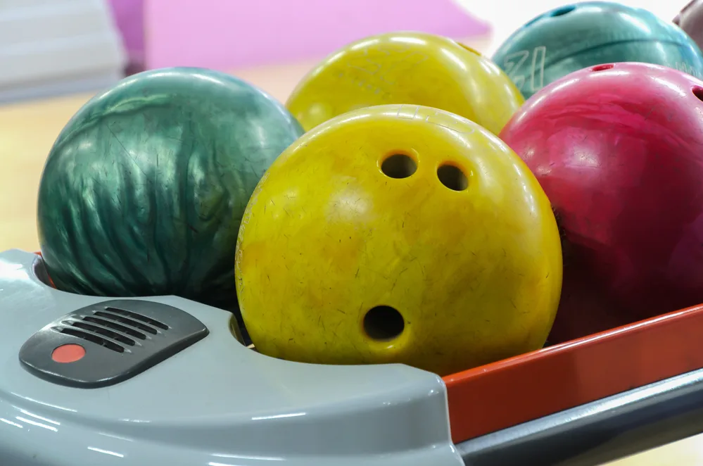 Different color bowling balls sitting on a ball return that will be used in upcoming tournaments