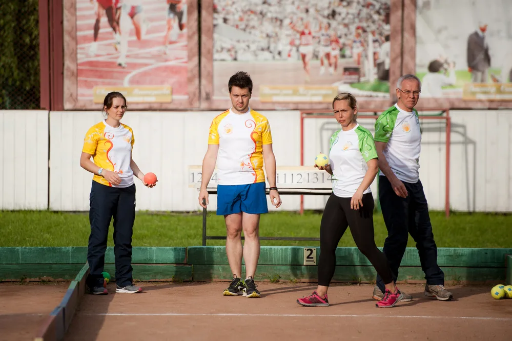 Bocce players in a tournament wearing yellow and green shirts