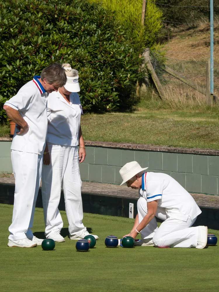 Dressed in white, the umpire of the match, measures bowls distance from the jack at a match in isle of thorns.