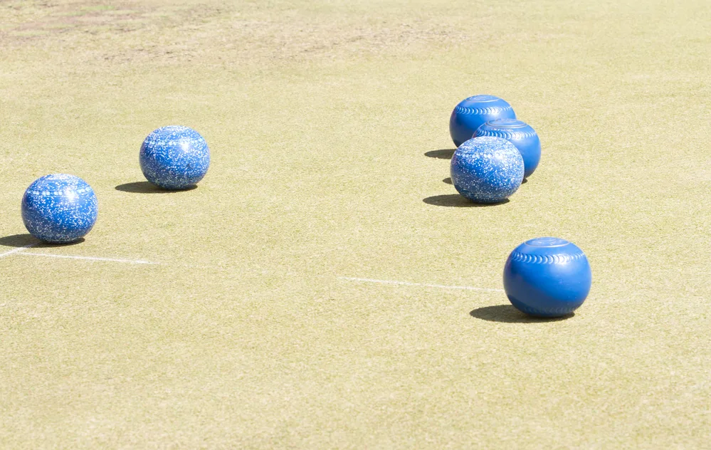 Three-person team, all using blue bowls on very low-cut grass
