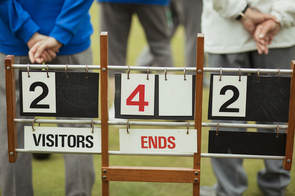 A lawn bowling scoreboard on grass, showing shots scored and the single digit score.