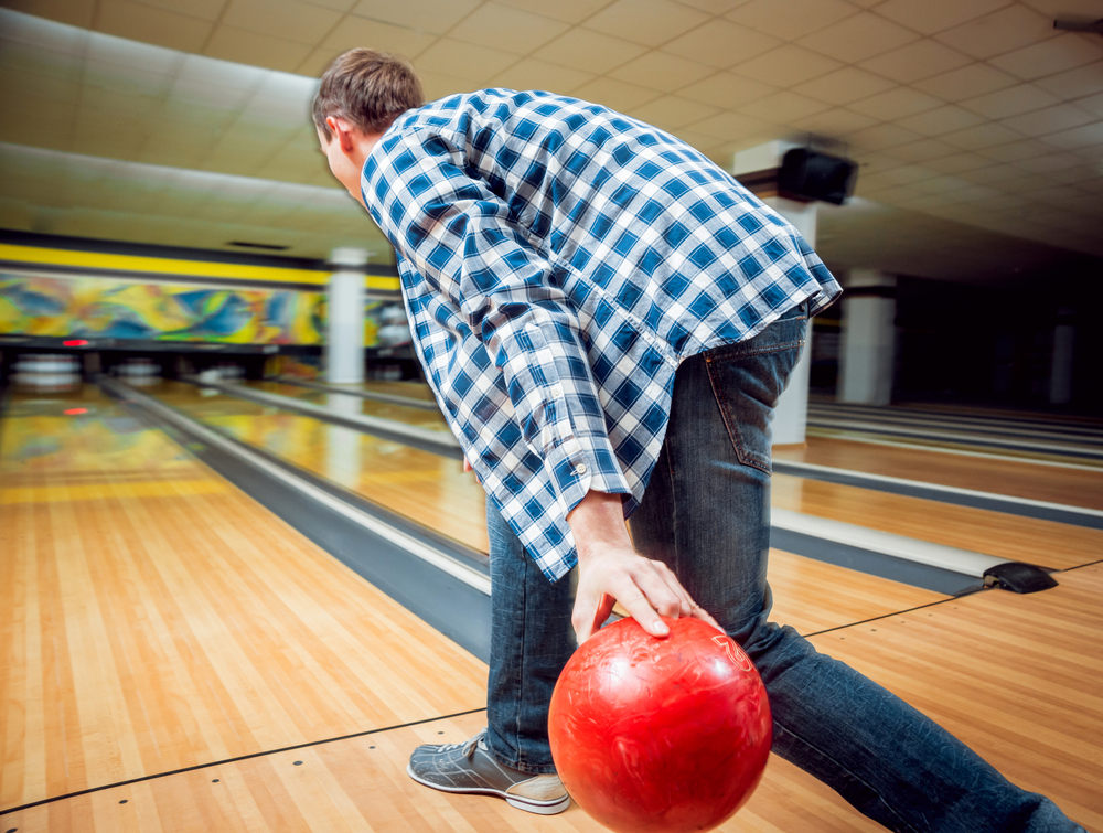 Young man at the bowling alley with the ball on ten pin bowling lanes