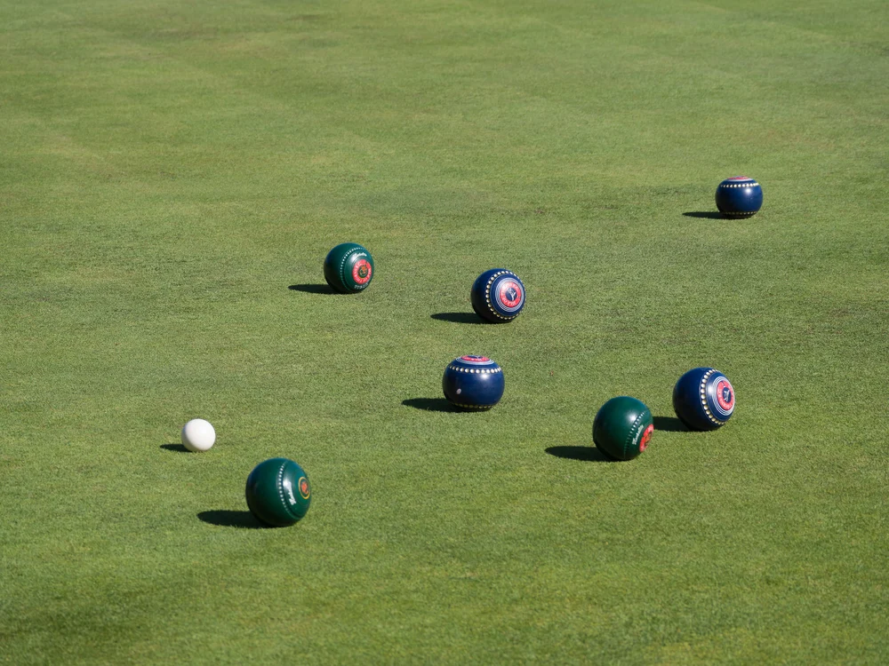 Various colorful bowls on a manicured green with a white jack