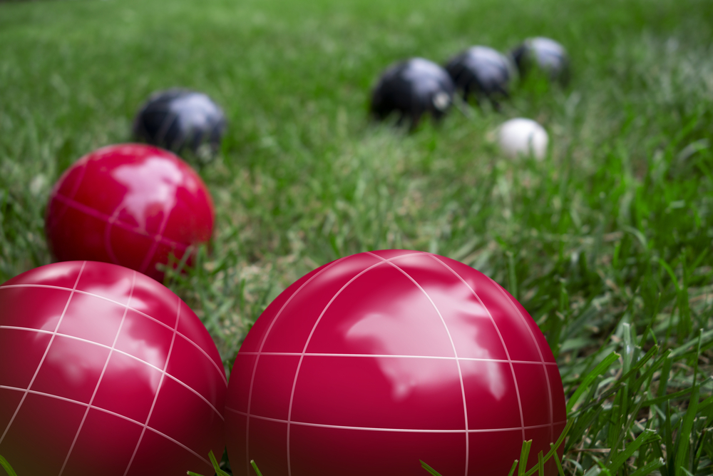 Red and dark blue bocci balls on a green grass lawn playing the game