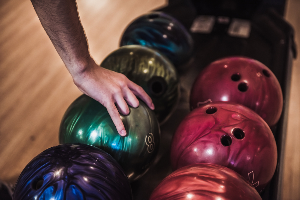 Man's hand choosing a good bowling ball because its the best bowling balls for league bowlers